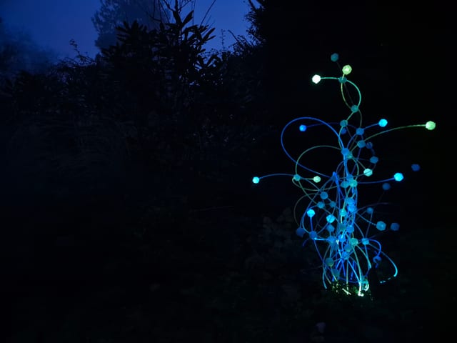Sculpta — cyan glowing outdoor light sculpture with hexagonal nodes at night