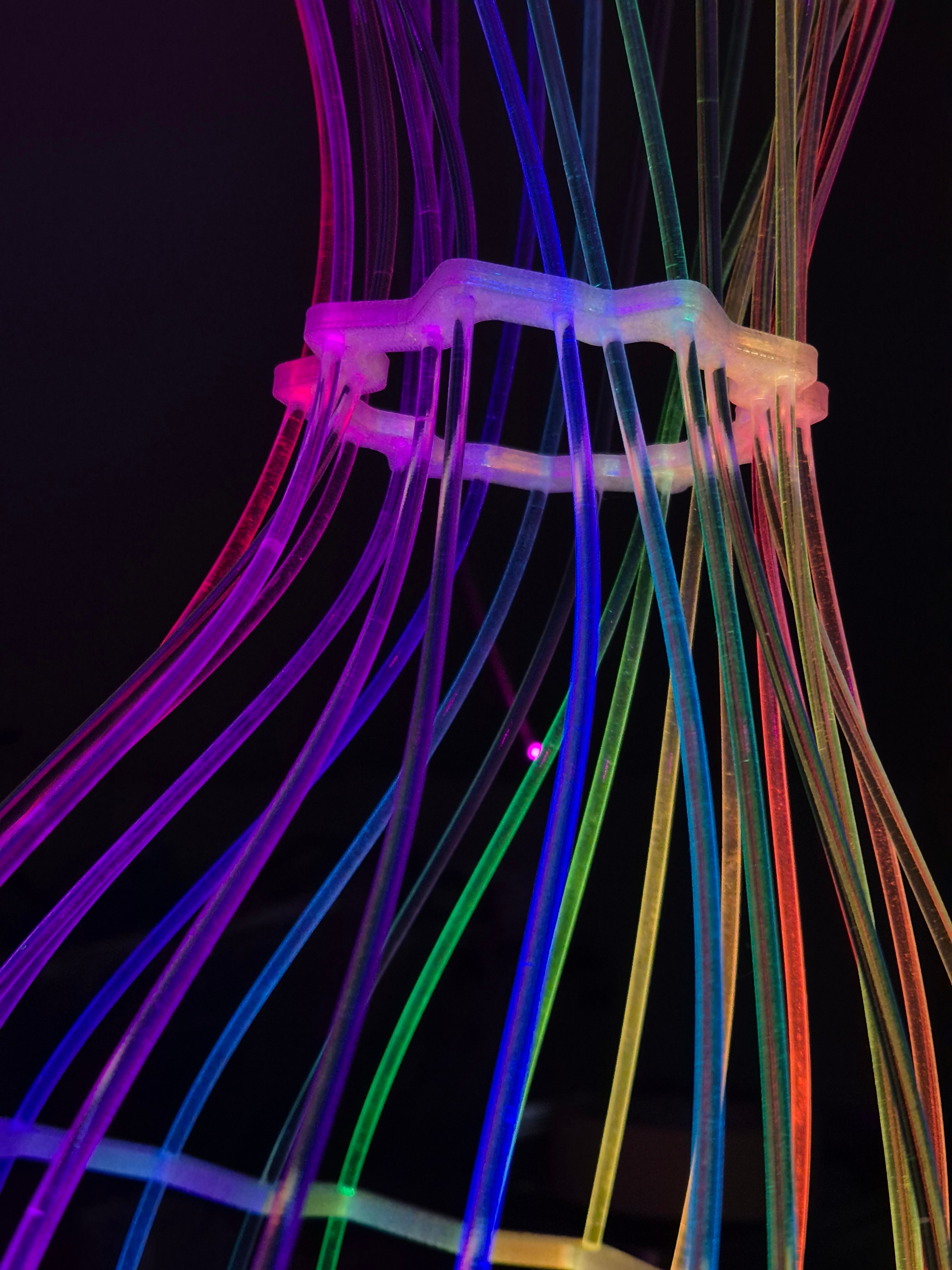 Fiberina — close-up of rainbow fiber-optic rods held by a 3D-printed bracket