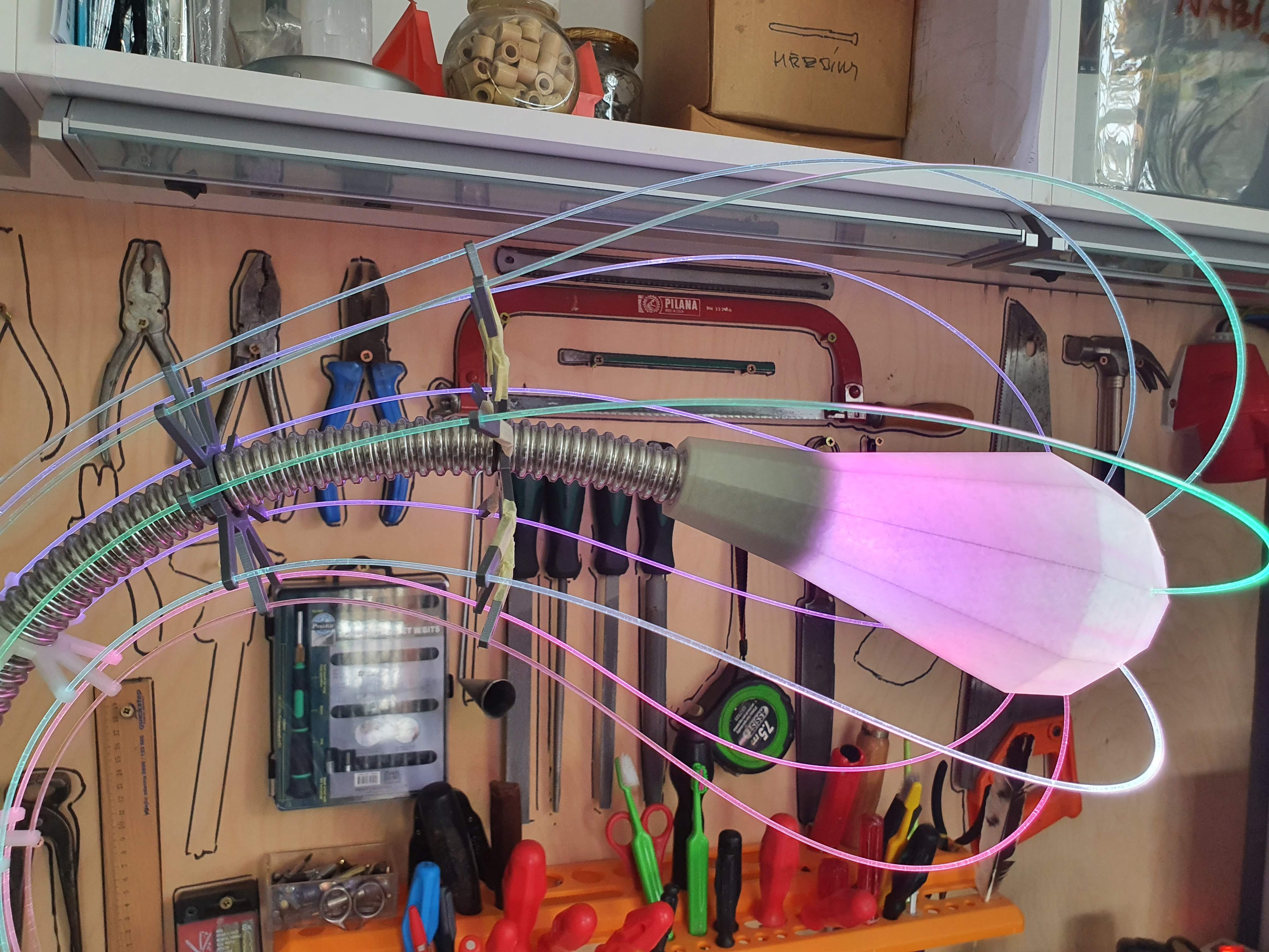 IXFID — close-up of glowing lamp head with green and pink strands in a workshop