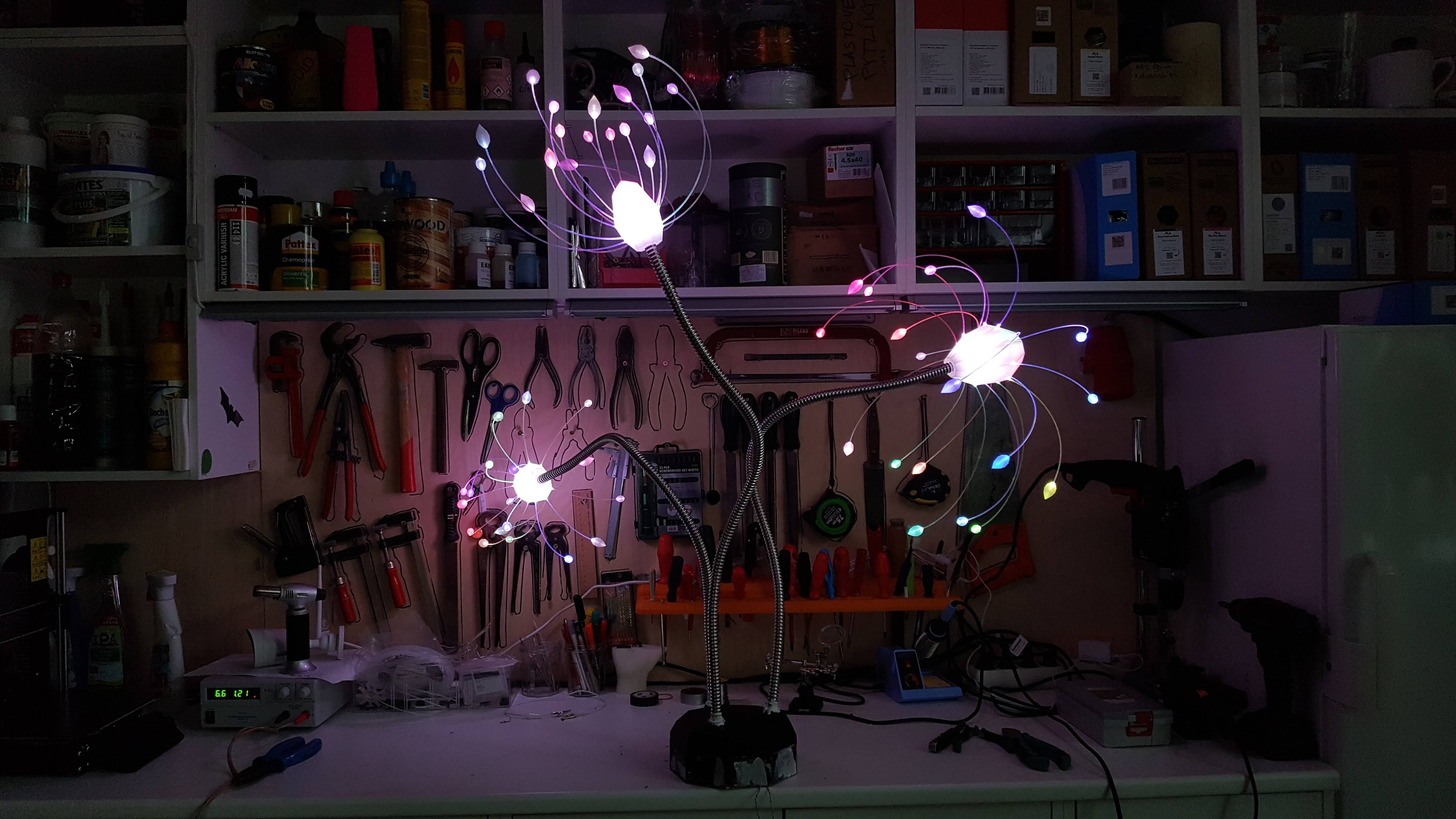 Tris — wide shot of three glowing garden sculptures at night