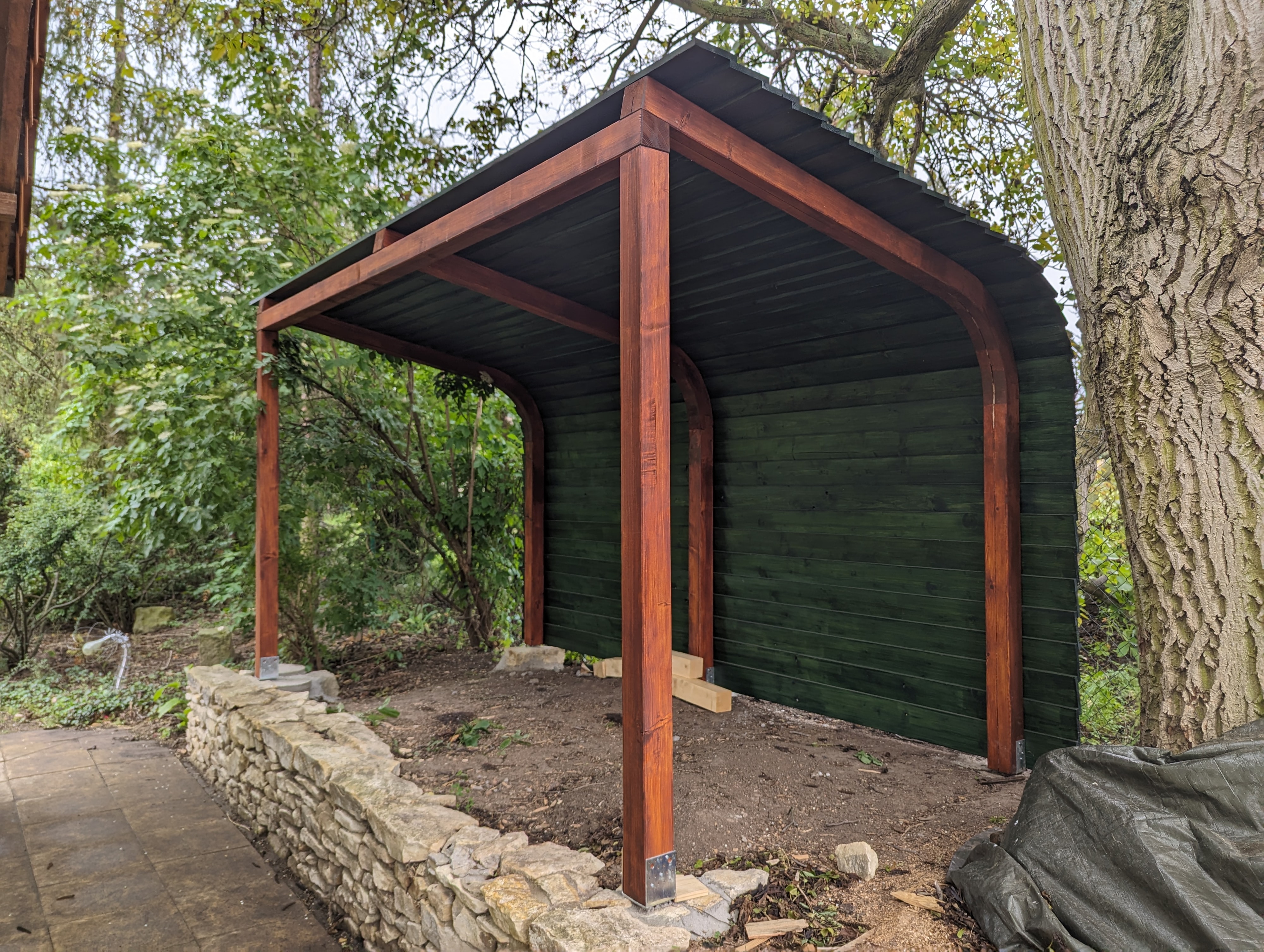 Woodgon — woodshed side view with mesh panels and stacked logs