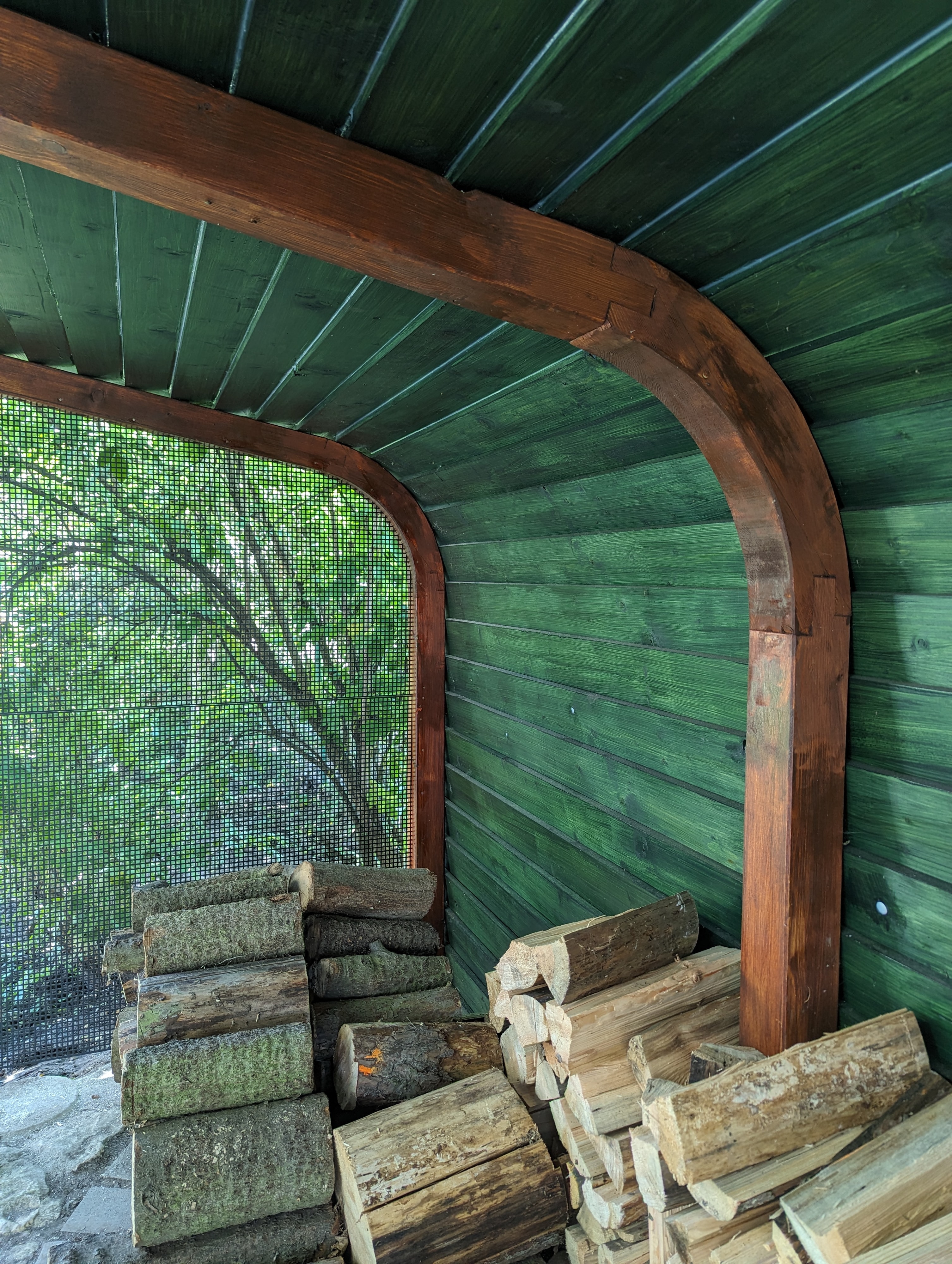Woodgon — stacked firewood inside a green-planked woodshed