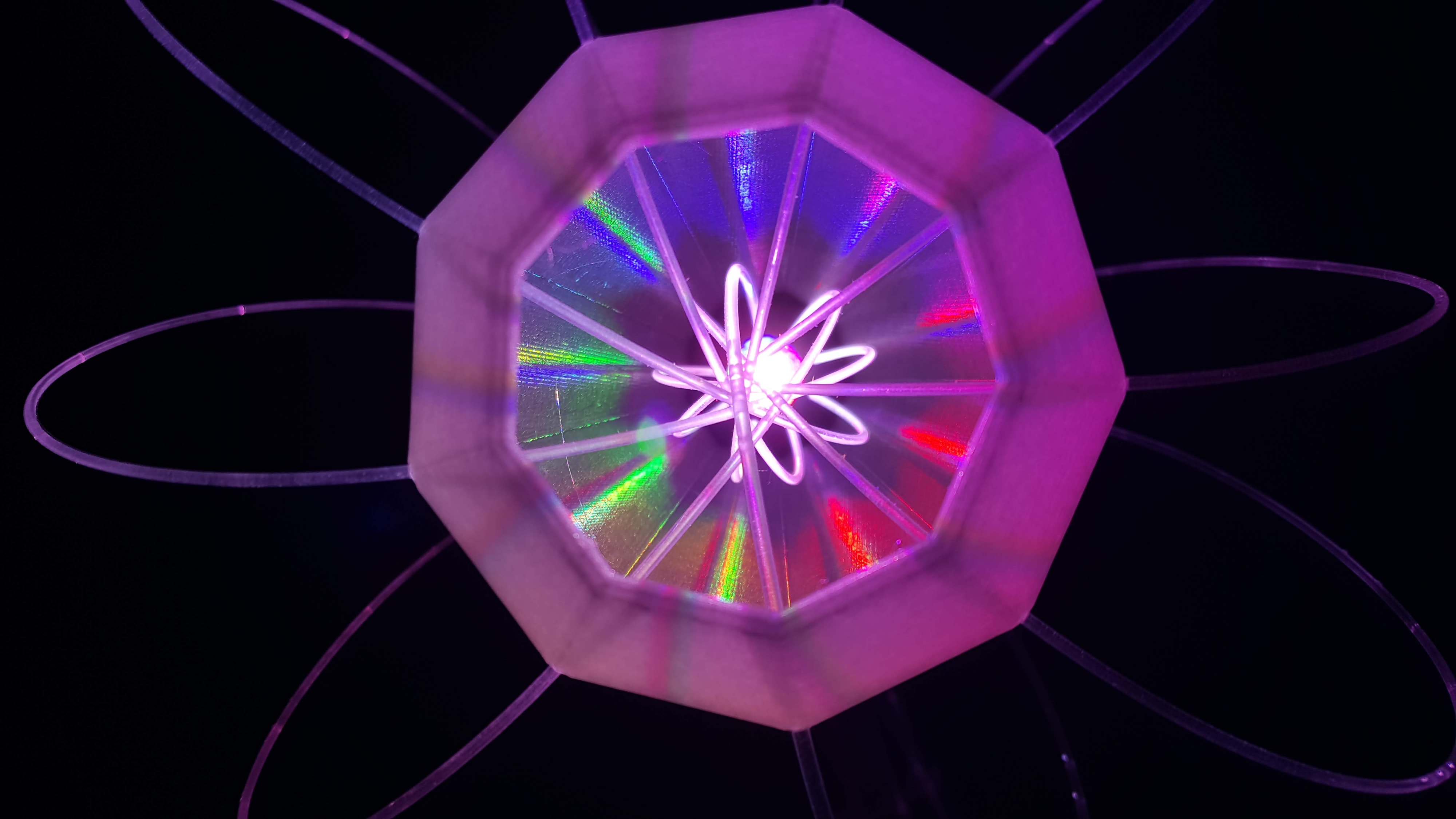 IXFID — glowing purple geometric atomic-flower light sculpture on black background