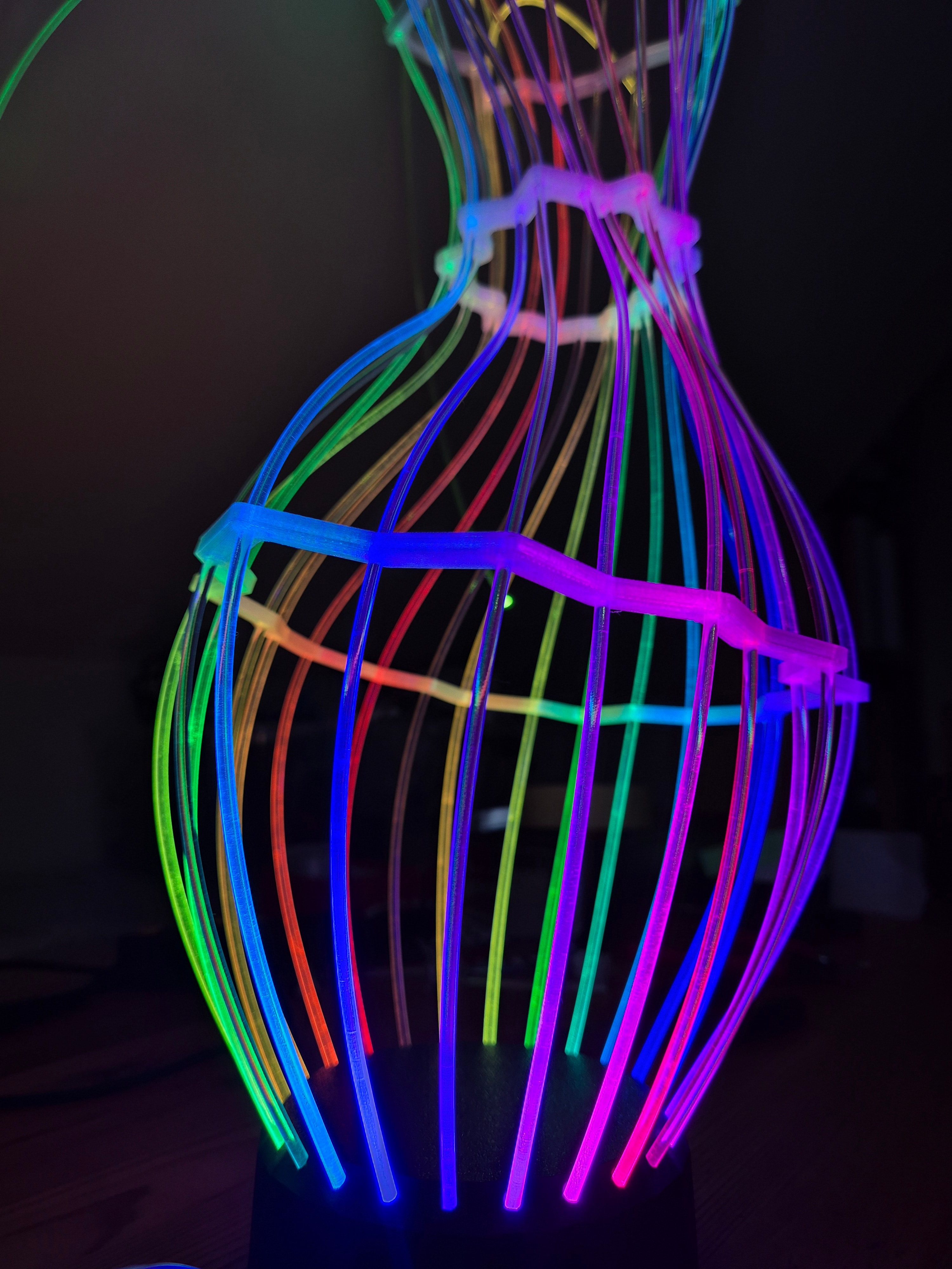 Fiberina — rainbow-lit vertical rods in a vase-like cage structure