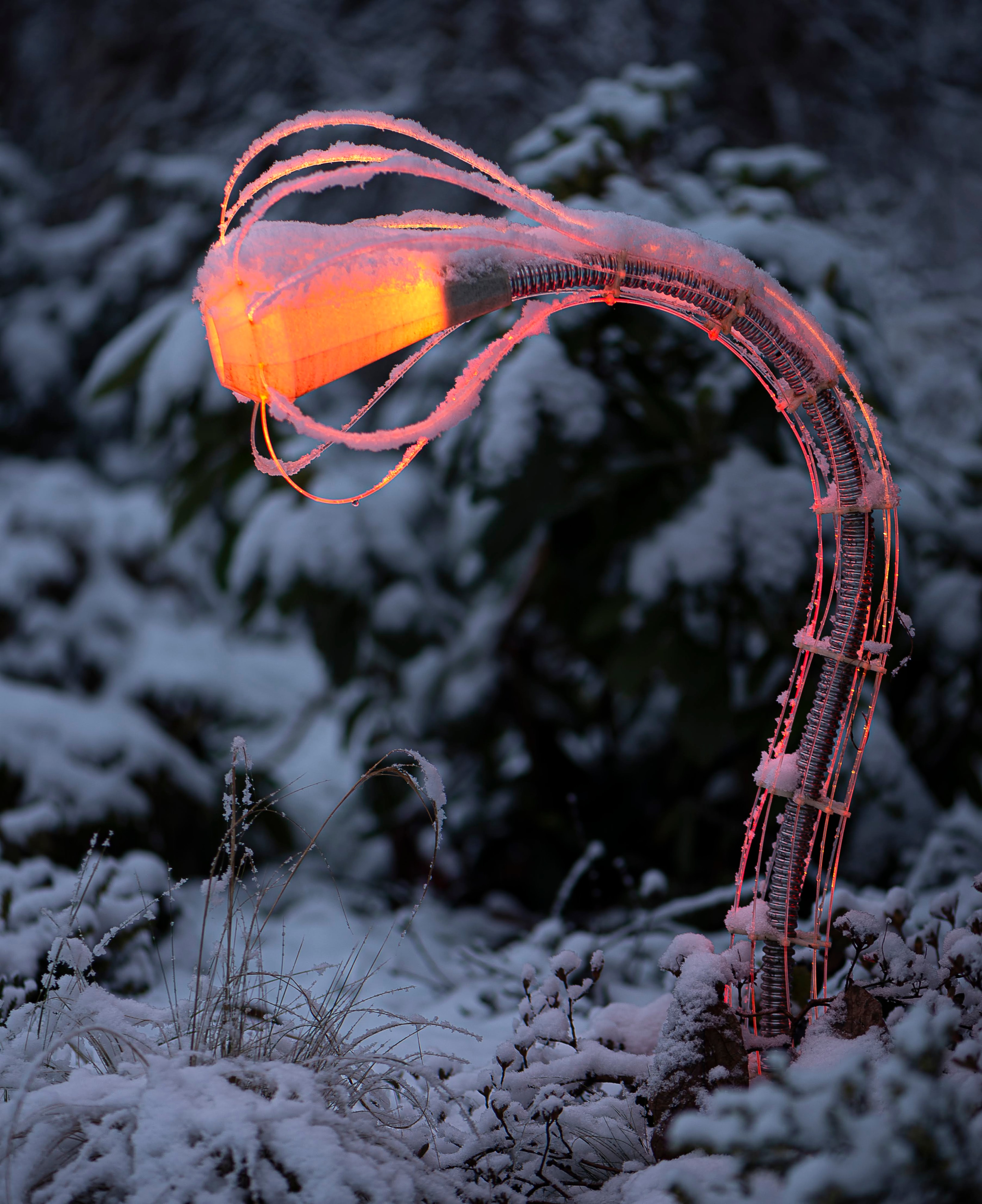 IXFID — curved outdoor lamp glowing orange in a snowy garden