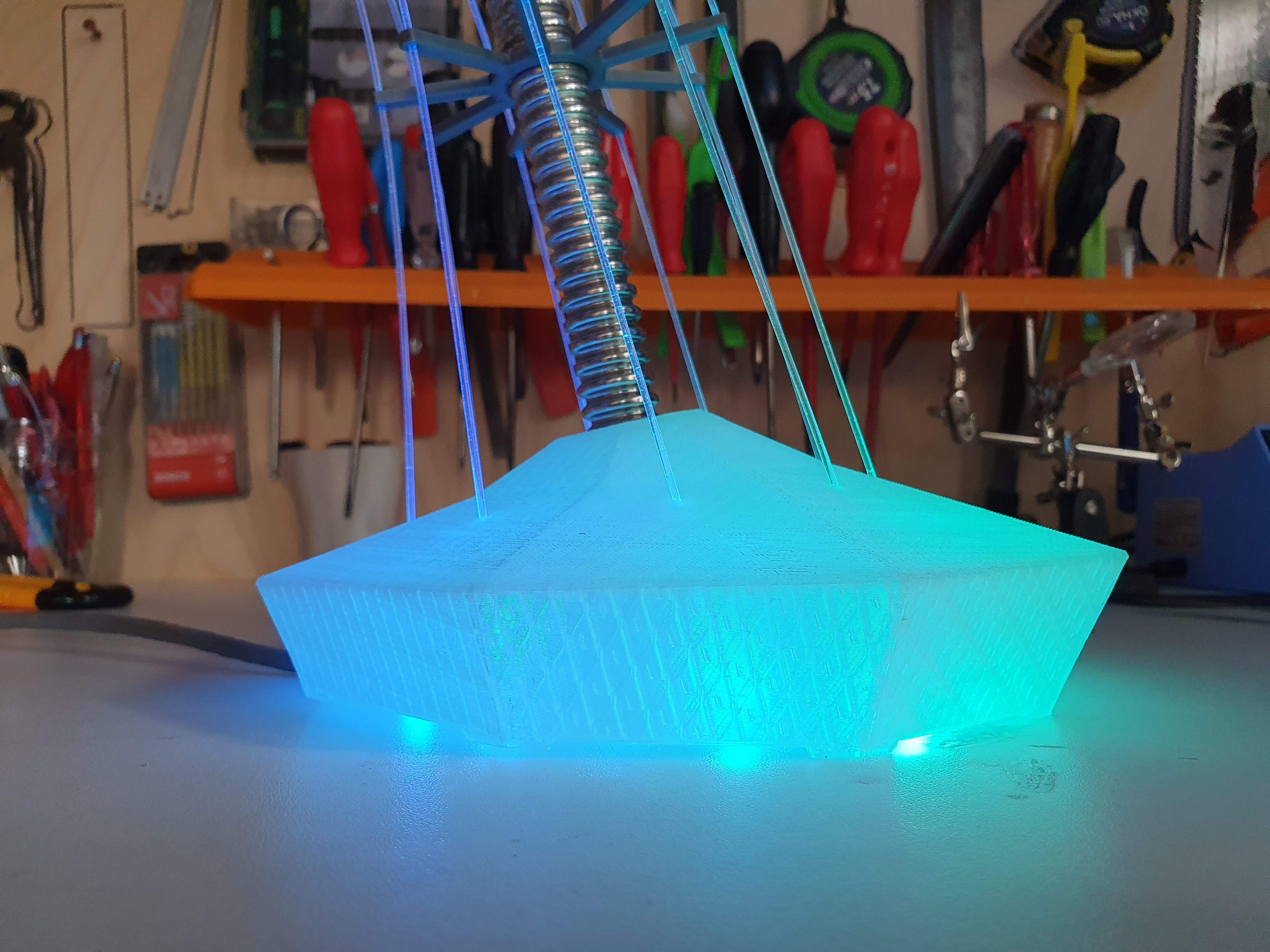 IXFID — glowing blue-green 3D-printed lamp base on a workbench